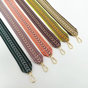 Detail of seven thick embroidered bag straps with colorful geometric patterns and gold clips