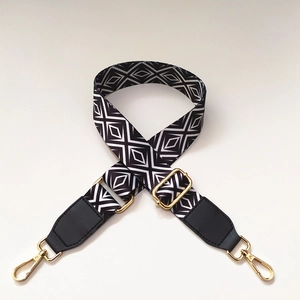 Detail of black and white geometric diamond pattern strap with gold metal swivel hooks