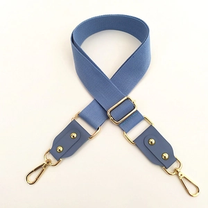 Detail of adjustable blue cotton strap with golden metal buckles and leather attachments