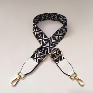 Detail of black and white geometric pattern bag strap with gold metal lobster clasps