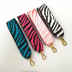 Dettaglio di quattro tracolle ricamate a motivo zebra con ganci in metallo dorato