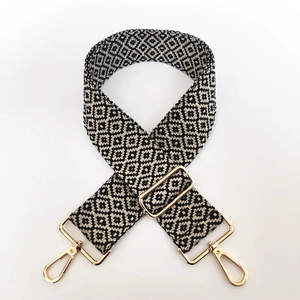 Close-up of geometric embroidered cotton bag strap with polished gold-tone metal hardware