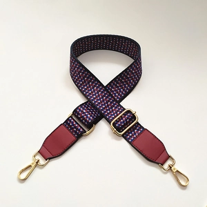 Detail of adjustable wide woven bag strap with colorful geometric pattern and gold hooks