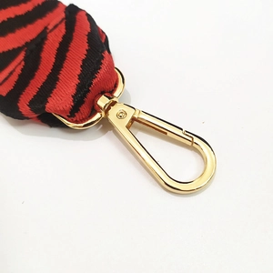 Détail de la bandoulière en coton zèbre rouge et noir avec fermoir mousqueton doré