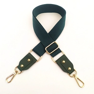 Detail of adjustable dark green wide cotton bag strap with gold hardware hooks