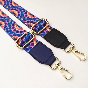 Detail of adjustable wide purse strap with pixel floral pattern and gold metal buckles
