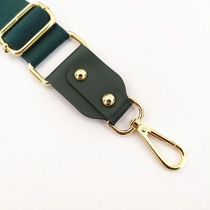 Detailed view of dark green shoulder strap with premium golden hardware and black leather joint