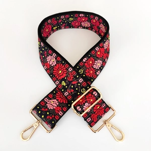 Close-up of bohemian floral embroidery on wide bag strap with gold metal hardware