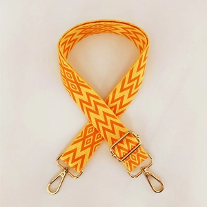 Detail view of ethnic geometric woven pattern on adjustable bag strap with gold metal hooks