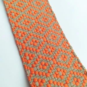 Macro detail of high-density ethnic woven shoulder strap with orange geometric patterns