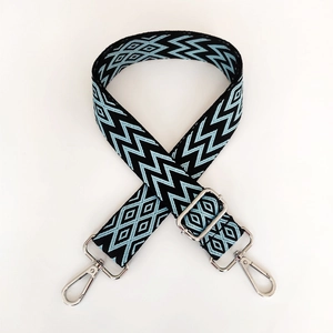 Detail of blue geometric embroidered bag strap with silver metal swivel hooks