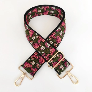 Close-up of vintage floral embroidery on wide black adjustable strap with gold hooks