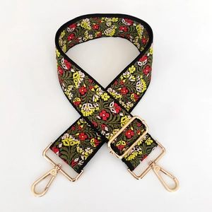 Close-up of ethnic floral embroidery on a wide adjustable shoulder strap with gold hooks