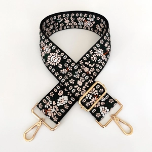 Close-up of adjustable jacquard bag strap with floral embroidery and gold metal clips