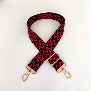 Close-up of red and black geometric embroidery bag strap with gold metal lobster clasps
