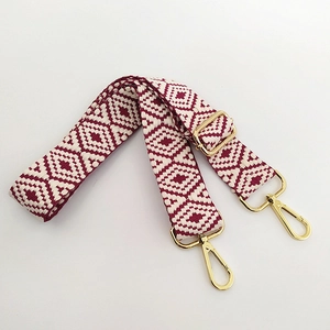 Detail of red and cream bohemian geometric woven strap with golden lobster clasps