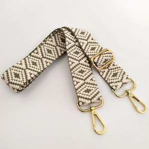 Macro detail of adjustable jacquard bag strap with olive green geometric diamond patterns