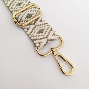 Close-up of geometric jacquard bag strap with gold lobster clasp and metal buckle