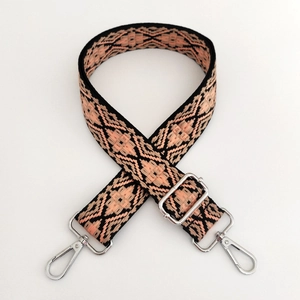 Close-up of pink and black geometric jacquard bag strap with silver metal swivel hooks
