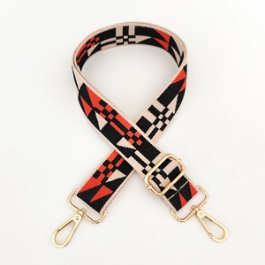 Close-up of wide adjustable shoulder strap with geometric patterns and gold lobster clasps