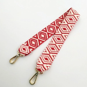 Close-up of ethnic red and white woven shoulder strap with gold metal swivel clasps