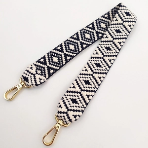 Close-up of black and white geometric diamond weave pattern bag strap with gold lobster clasps
