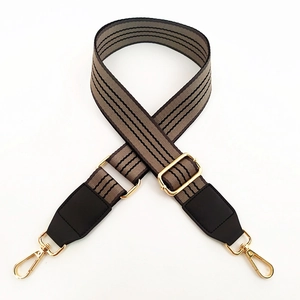Détail de la bandoulière rayée avec embouts en cuir et boucles métalliques dorées