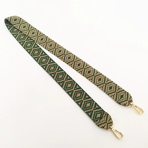 Close-up of bohemian green and brown geometric woven bag strap with gold lobster clasps