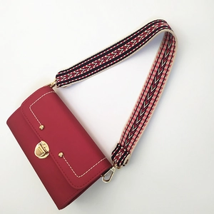 Détail du sac rouge avec large bandoulière brodée géométrique et fermoir doré chic