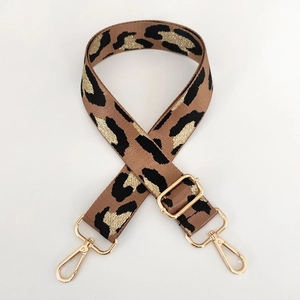 Detail of adjustable leopard print bag strap with golden metal hooks and jacquard texture