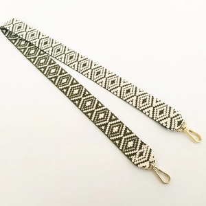 Close-up of olive green ethnic geometric woven strap with golden lobster clasps