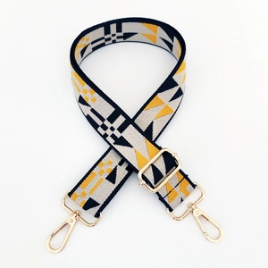 Detail of adjustable woven bag strap with yellow geometric pattern and gold buckles