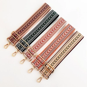 Five adjustable ethnic style woven purse straps with gold hardware on white background