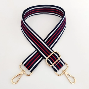 Detail of adjustable woven handbag strap with red white blue stripes and gold metal hooks