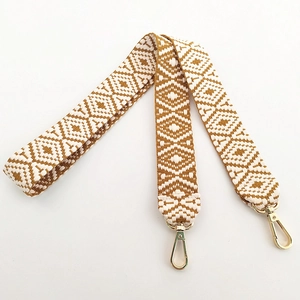 Detail of geometric pattern woven bag strap with golden lobster clasps for handbags