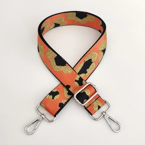 Detail of adjustable leopard print bag strap with orange weaving and silver metal hooks