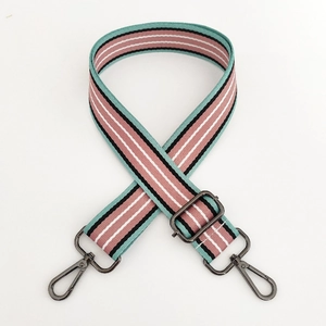 Detail of adjustable woven bag strap with colorful stripes and gray metal swivel hooks