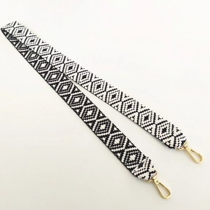 Close-up of black and white geometric woven bag strap with gold metal swivel hooks