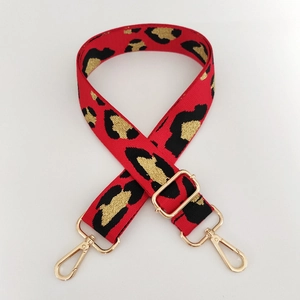 Detail of red leopard pattern wide bag strap with gold metal buckles and glitter weave