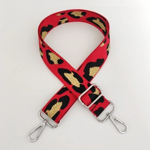 Detail of red leopard print woven bag strap with silver metal lobster clasps and buckles
