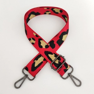 Macro shot of red leopard pattern bag strap with dark gunmetal swivel hooks