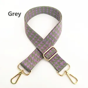 Adjustable woven shoulder strap featuring purple and green houndstooth pattern with gold buckles