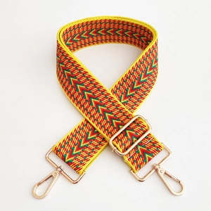 Detail of yellow ethnic embroidered bag strap with golden metal swivel hooks and thick weave