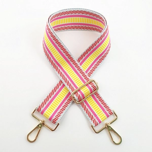 Detail of adjustable woven bag strap with colorful red and grey stripes and gold hardware