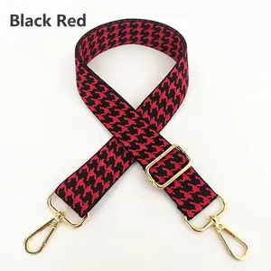 Detail of adjustable black and red houndstooth strap with golden metal swivel hooks