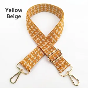 Close-up of yellow and beige houndstooth bag strap with adjustable gold metal buckle