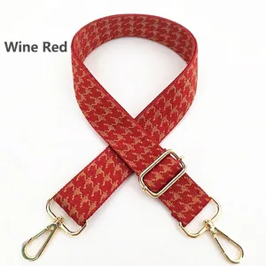 Detail of wine red houndstooth wide bag strap with adjustable gold hardware