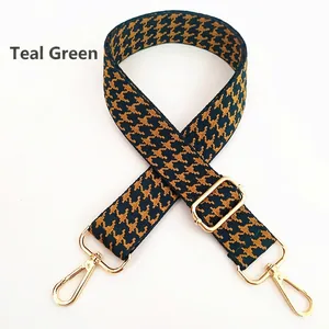 Detail of adjustable green and mustard houndstooth bag strap with gold metal hooks