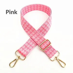 Detailed view of pink houndstooth wide strap with adjustable gold hardware buckles