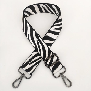 Macro view of zebra pattern canvas bag strap with gunmetal swivel hooks and adjustable buckle